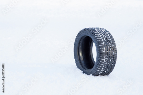 Black rubber tire rolling on the soft, fresh snow in the sunny day. White background. Seasonal tire change. © fotoduets