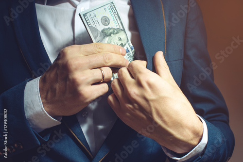Фотография man businessman taking notes in pocket as a bribe