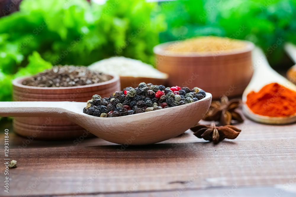 Beautiful colorful spices in wooden spoons on an old brown table. Free space for your text