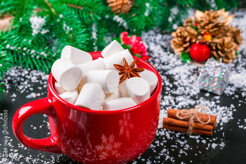 Beautiful Christmas background with Cup of marshmallows,  the Christmas tree branches, snow and Christmas decor on black table