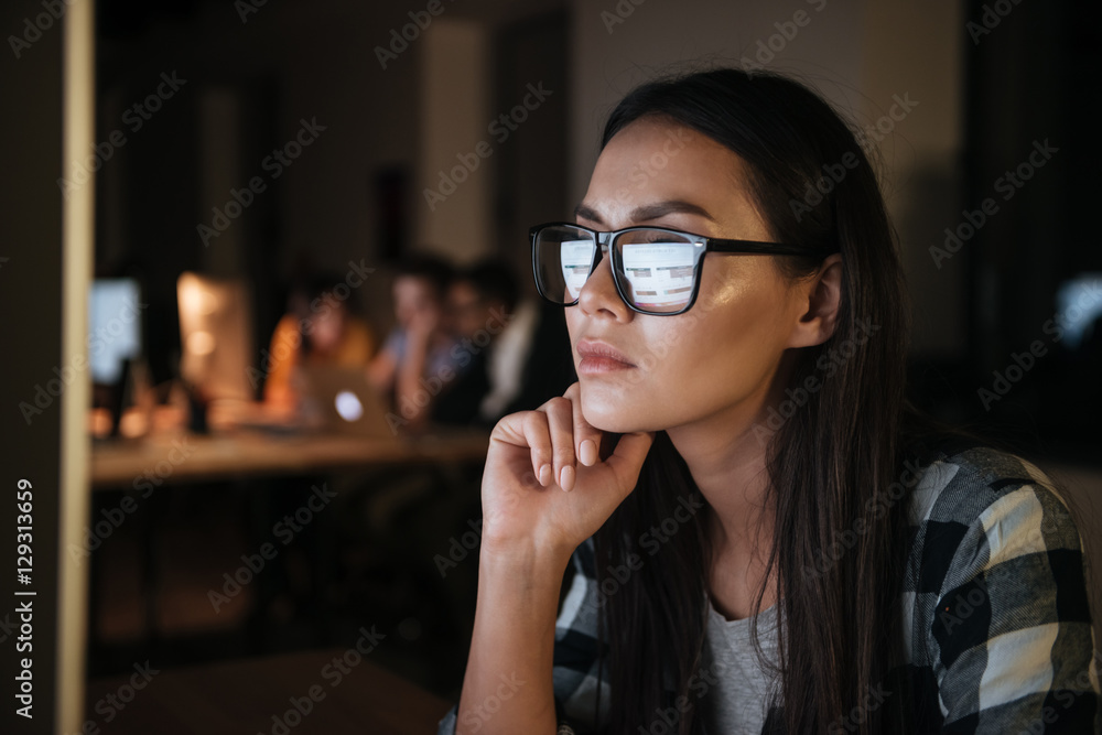 Serious businesswoman wearing glasses working late at night Serious businesswoman wearing glasses working late at night