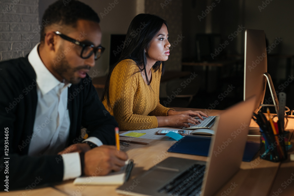 African businessman and woman working late at night in office