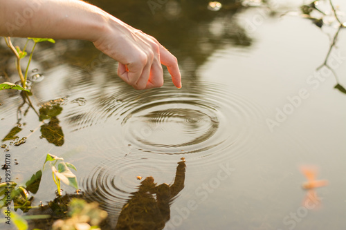 Close up finger touches water and drop of water falling and creating natural and calm waves,calmly concept,