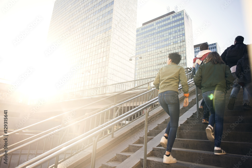 Low angle view of friends walking up on steps by buildings in city