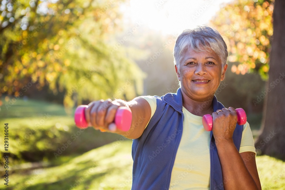 Smiling mature woman exercising with dumbbell Smiling mature woman exercising with dumbbell
