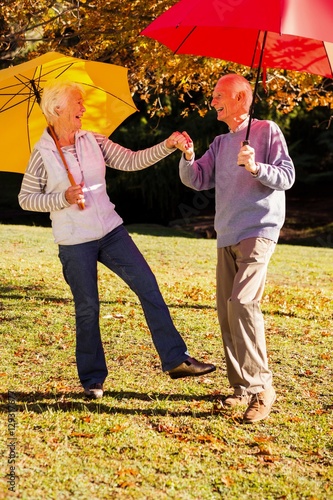 Senior couple dancing with umbrellas photo