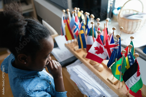High angle view of thoughtful girl looking at various flags in classroom photo
