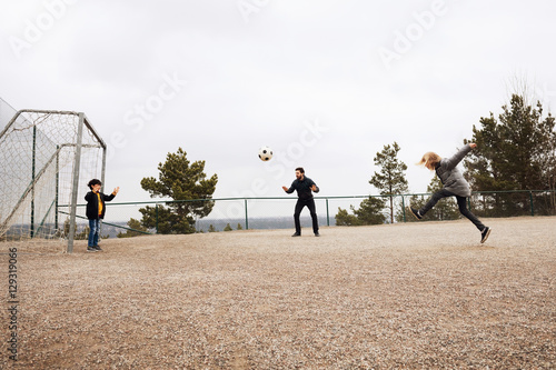 Teacher guiding students while playing soccer on school playground photo