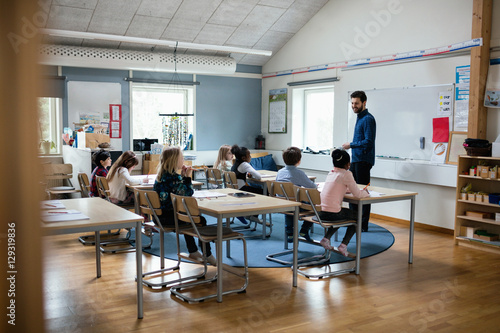 Confident teacher teaching students in classroom at school