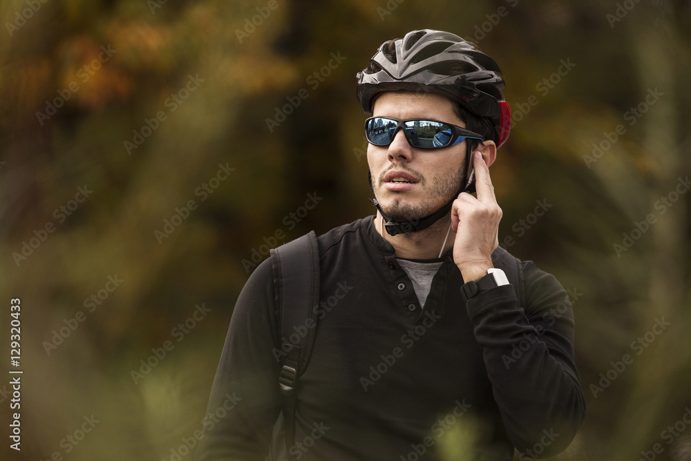 Man with his bike talking on handsfree, in the middle of nature