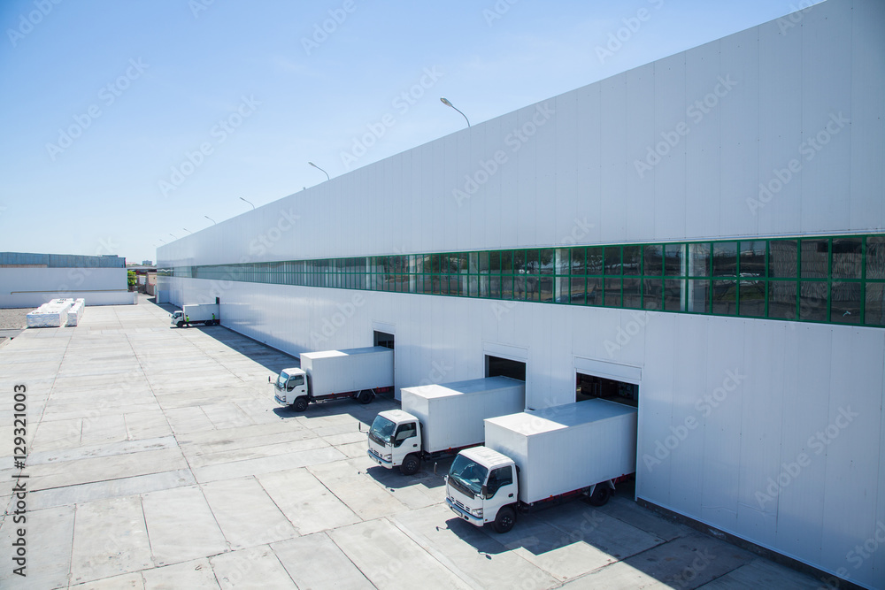 facade of an industrial building and warehouse with freight cars in length - obrazy, fototapety, plakaty 