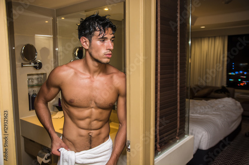 Handsome shirtless muscle young man going out of shower in hotel room. Horizontal indoors shot