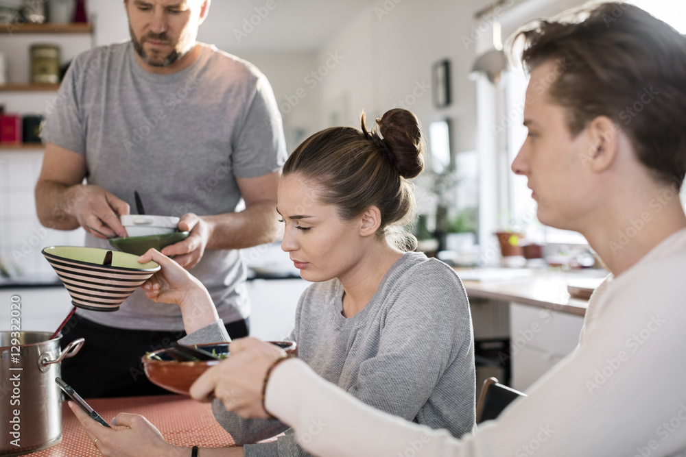 Brother and sister giving bowls to father in kitchen Brother and sister giving bowls to father in kitchen