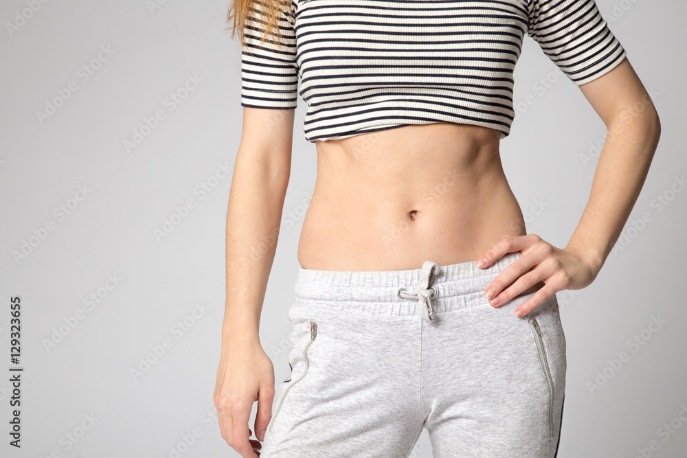 A woman showing her slim waist. Beautiful slim woman body in sportswear.  One hand on the waist, the other is down. Stock Photo