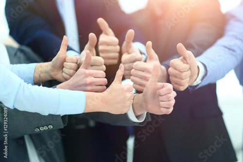 Photos Close-up of business team holding their thumbs up