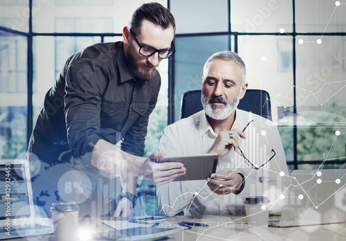 Concept of digital screen,virtual connection icon,diagram, graph interfaces.Young bearded man showing startup idea on mobile tablet.Adult businessman working together with partner.Film effect,blurred.