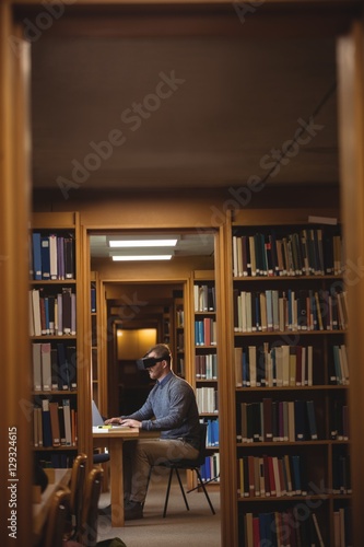 Mature student in virtual reality headset using laptop