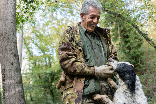Truffle hunter trying to get black truffle out of mouth of his d