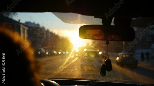 The man driving the car under sunset sky reflection in the rear view mirror