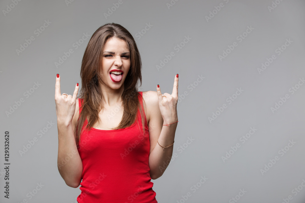 Young brunette woman showing rock and roll hand gesture posing in studio. Young brunette woman showing rock and roll hand gesture posing in studio.