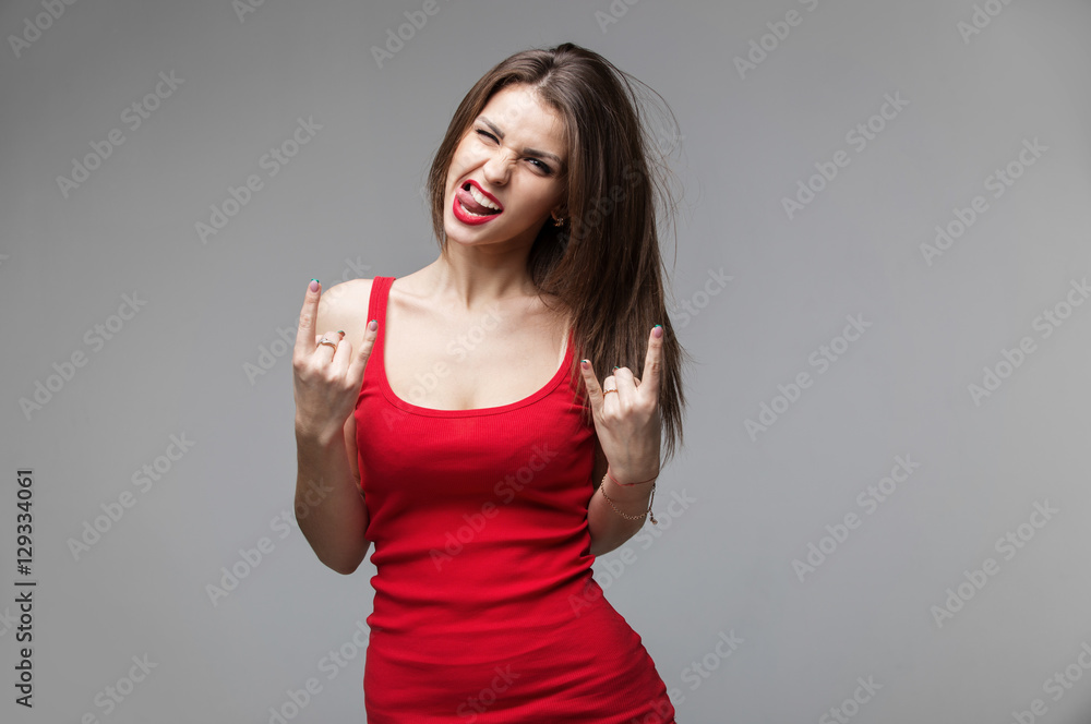 Young brunette woman showing rock and roll hand gesture posing in studio. Young brunette woman showing rock and roll hand gesture posing in studio.