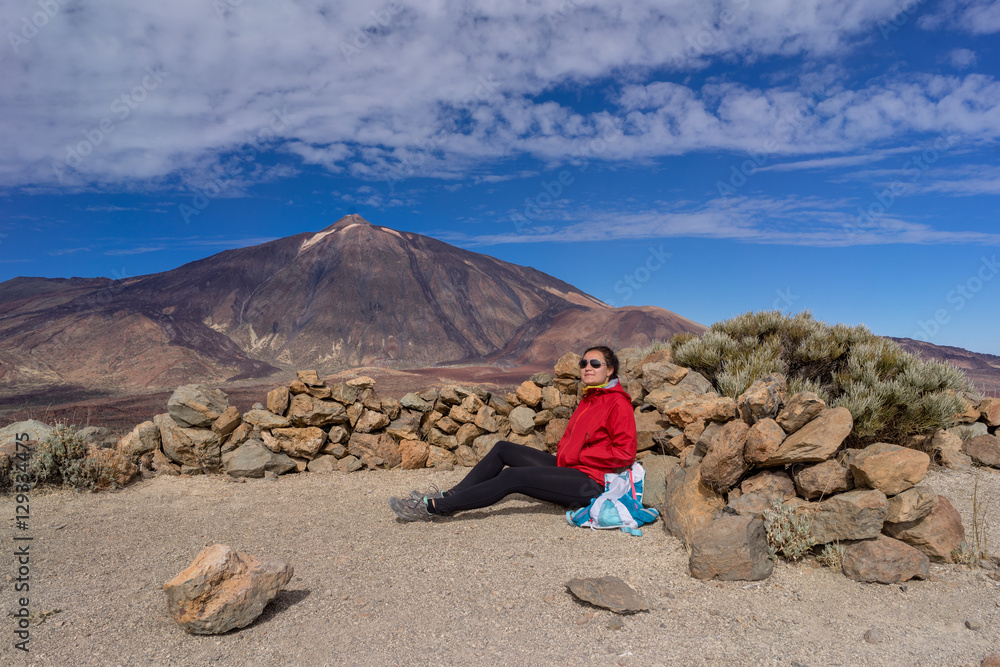 Obraz premium Young female hiker is resting with beautiful view of Mount Teide volcano. Tenerife, Canary Islands, Spain.