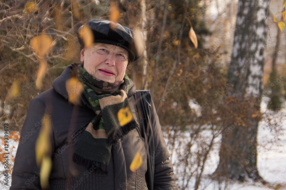 Portrait of old woman posing in winter park, close up