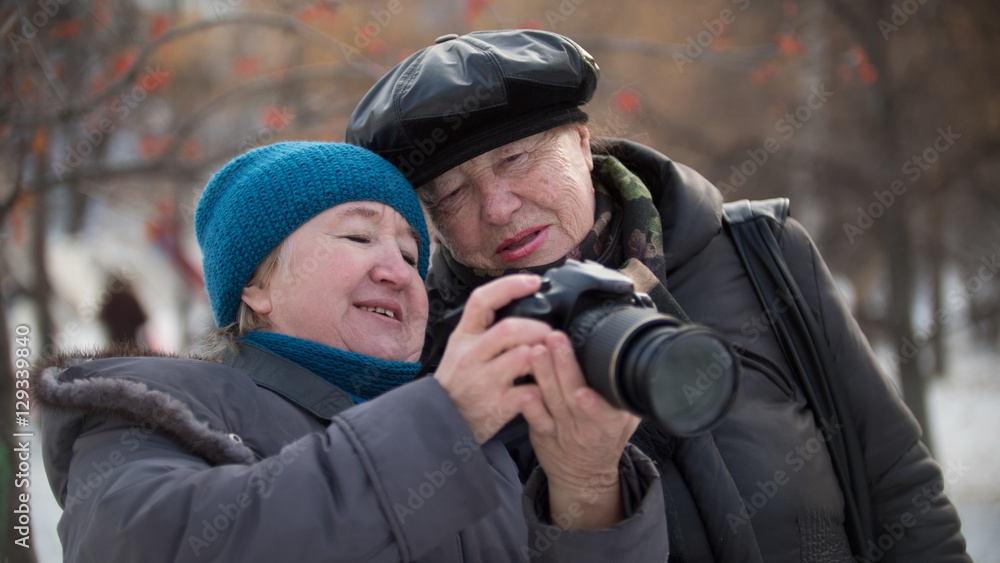 Obraz premium Two senior woman looking to they self photo camera at winter day, outdoor