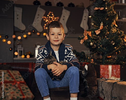 A boy playing with a cat in a room with Christmas holiday decora © Fxquadro