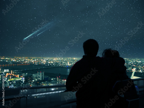 Couple looking over Osaka night skyline and falling stars