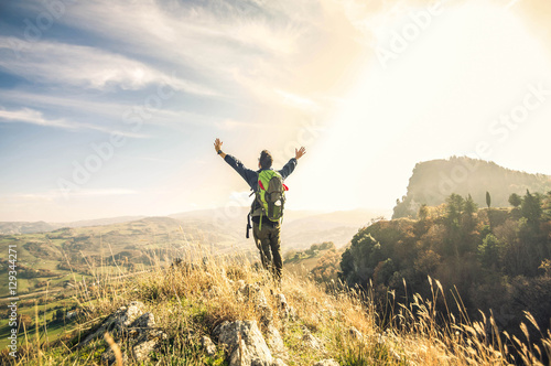 Cuadro en lienzo Man standing on a ledge of a mountain, enjoying the beautiful sunset