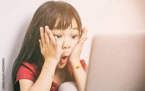 Little Asian girl is shock with what she see on the Internet. Parent should be more careful on how their kid using the computers. photo