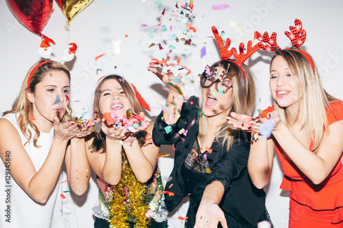 Four young woman blowing confetti and having fun 