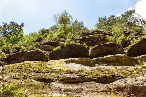 Low angle shot of multiple layers of rocks with greenery covering them in certain parts