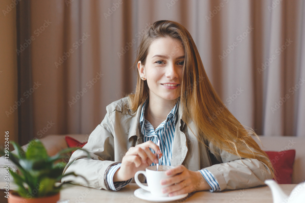 Beautiful young woman in beige autumn coat with cup of tea Beautiful young woman in beige autumn coat with cup of tea