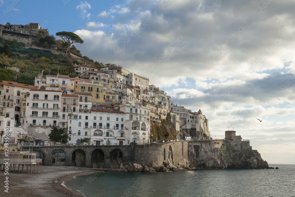 Postcard view of the beautiful town of Amalfi in the morning light. Gulf of Salerno, Campania, Italy. Blue sky background with clouds
