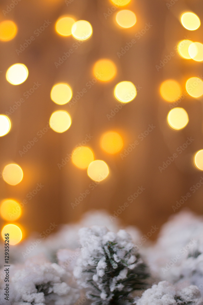 Christmas-tree branch under snow on a background of yellow light