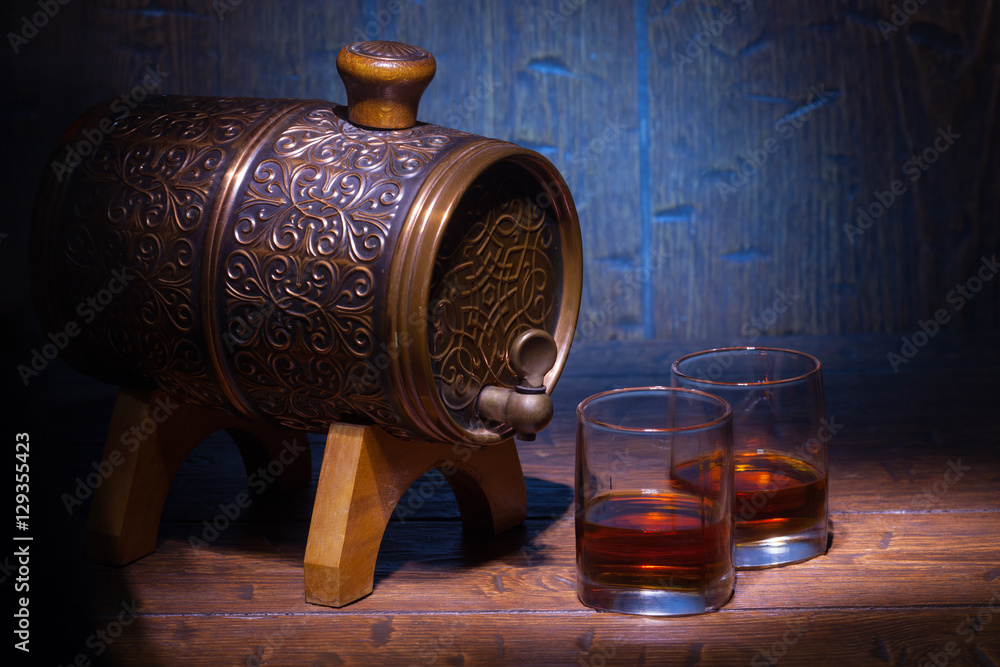 Glasses of whiskey and small barrel on wooden table