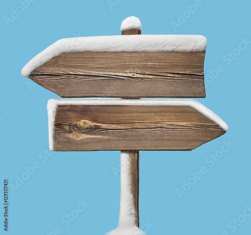 Wooden direction sign with snow on blue. two_arrows-opposite_direction photo