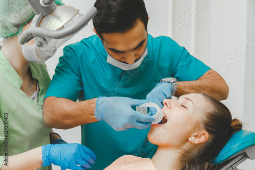 Doctor dentist puts the retractor to the patient mouth photo