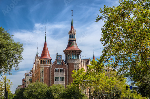 View on fabulous Casa de les Punxes in green trees and blue sky, Barcelona Spain