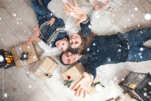 Family, mom, dad, son and are looking up, laughing, and pleased, to catch the snow on Christmas Eve/Family portrait