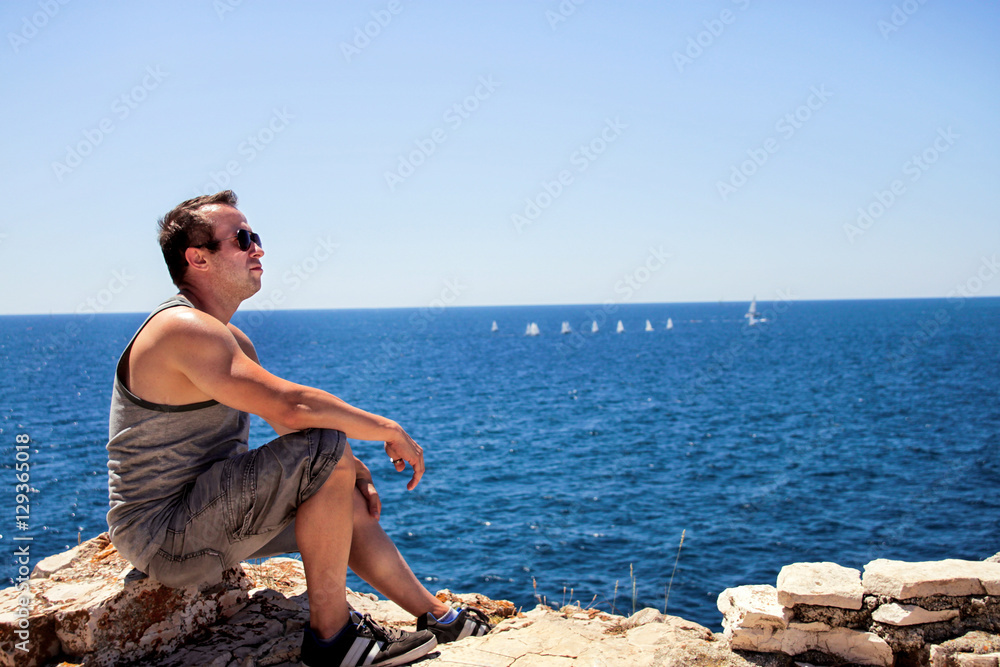 He is sitting by the sea and thinking about life