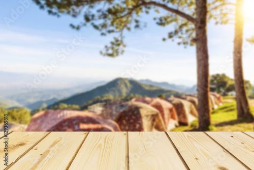 Wooden board empty table in front of blurred background of  tent for camping in the mountain with pine trees and sea of fog and flare used for mock up for display or montage your products, vintage.