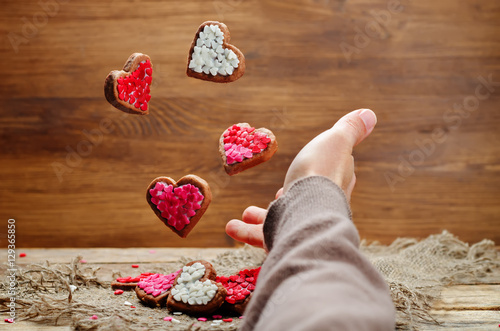 Male hand with flying cookies in the forms of hearts