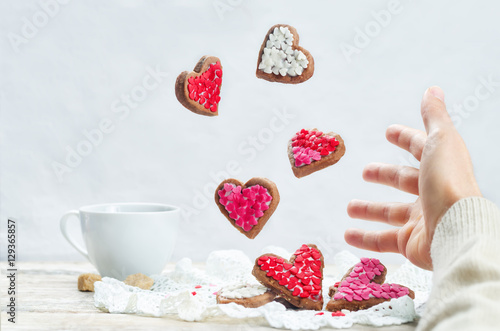 Male hand with flying cookies in the forms of hearts