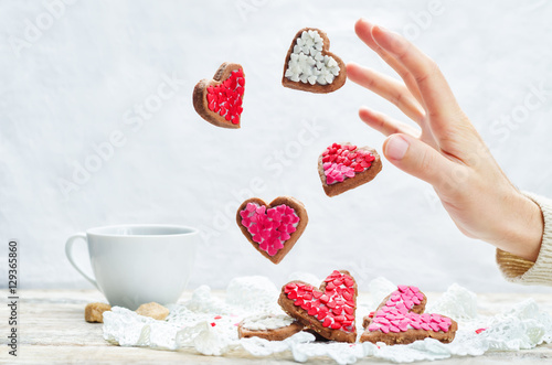 Male hand with flying cookies in the forms of hearts