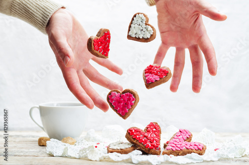 Male hand with flying cookies in the forms of hearts