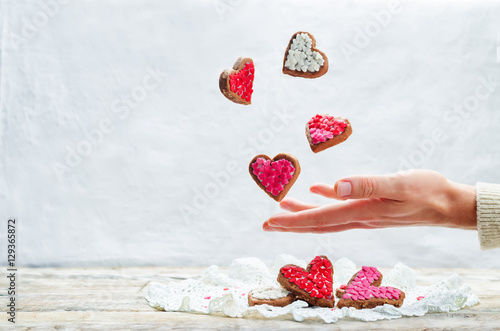 Male hand with flying cookies in the forms of hearts