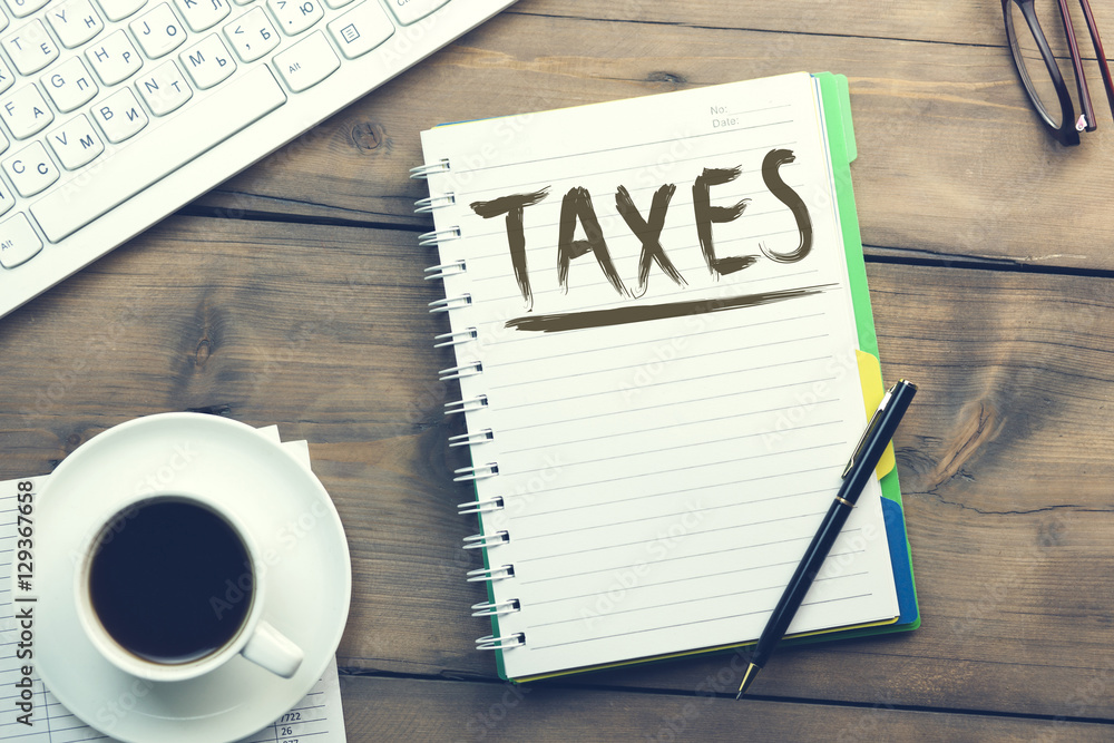 Taxes text on notebook with keyboard Taxes text on notebook with keyboard
